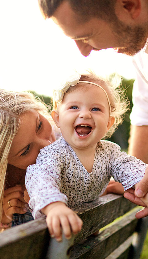 happy baby smiling with parents enjoying a sunny day in the park celebrating 19 moments together