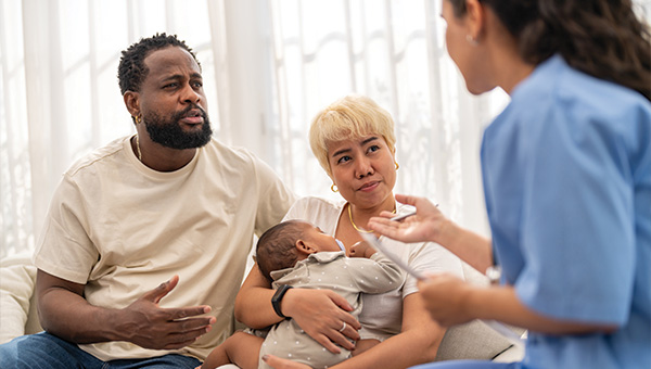 family discussing with healthcare provider while holding baby during consultation about parenting tips and baby care 9 essential tips for new parents