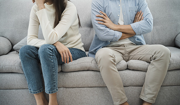 couple sitting apart on a sofa looking upset during a disagreement showcasing relationship issues possibly involving 12 steps to resolve conflict