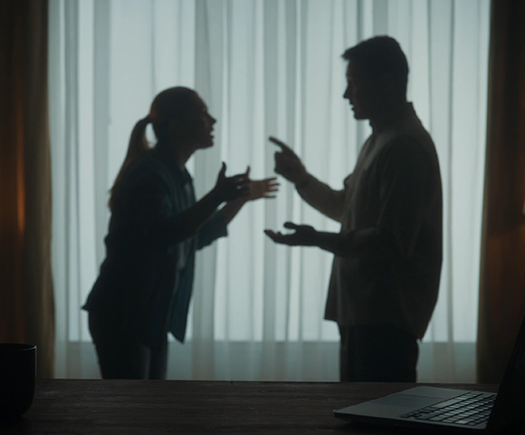 silhouettes of man and woman arguing by window with laptop on table depicting conflict and communication issues in relationships 5 tips for resolution