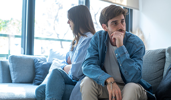 couple sitting back to back on couch looking distressed during argument two individuals in disagreement