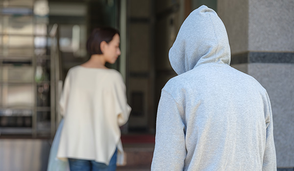 person in a gray hoodie watching a woman walking away in an urban setting demonstrating three elements of tension and anticipation