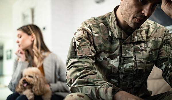 a soldier sitting with his head down while a woman looks away with a dog nearby depicting emotional tension in relationships the number 10 and its importance in military life